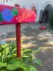 Rotes Holzschild mit der Aufschrift „Willkommen“ vor einem Hof