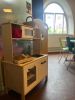pielecke mit kleiner Kinderküche in einem Raum mit Tischen und Stühlen