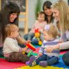 Erwachsene und Babys spielen gemeinsam in einer Krabbelgruppe