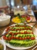 Teller mit Gurkenscheiben und Tomaten, im Hintergrund weiteres Buffet