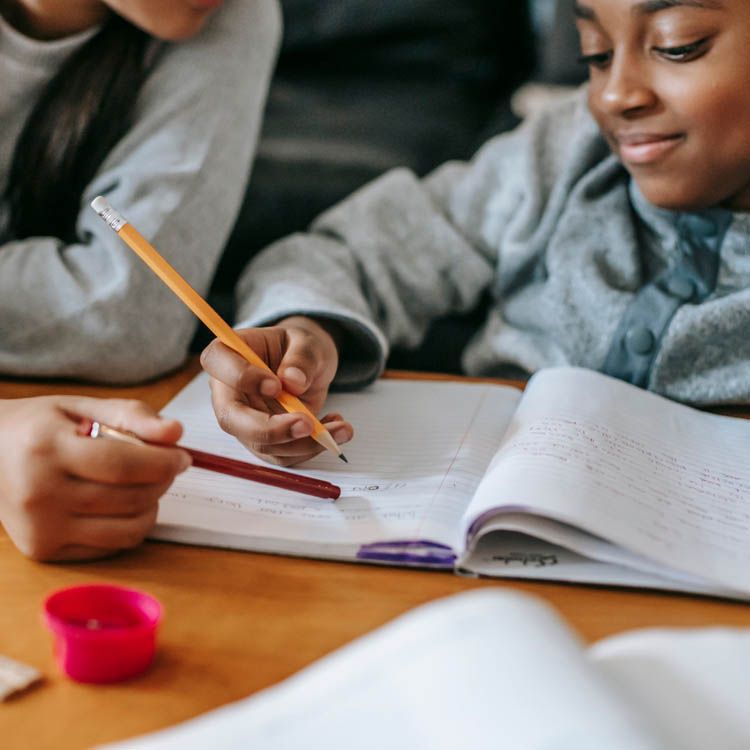 Zwei Kinder arbeiten gemeinsam in einem Schulheft