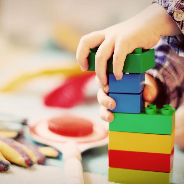 Kinderhand stapelt bunte Bauklötze
