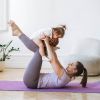 Mutter macht Yogaübung mit ihrem Baby auf der Matte
