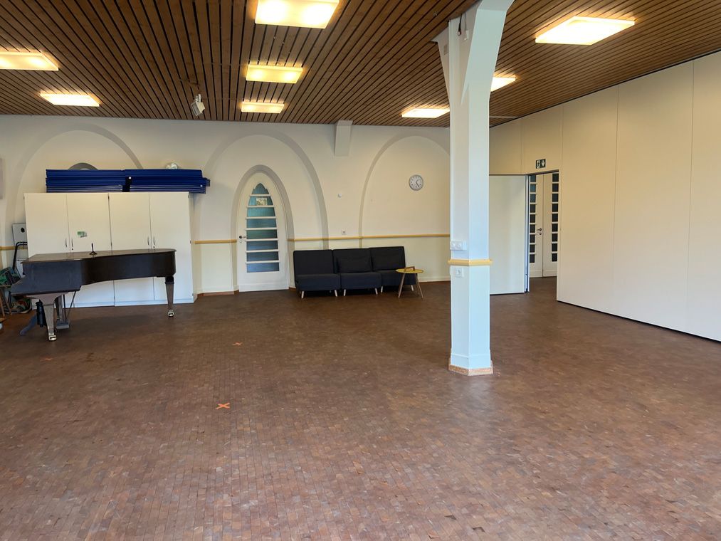 Großer Raum mit Klavier, Sofa und weißen Schränken an der Wand.