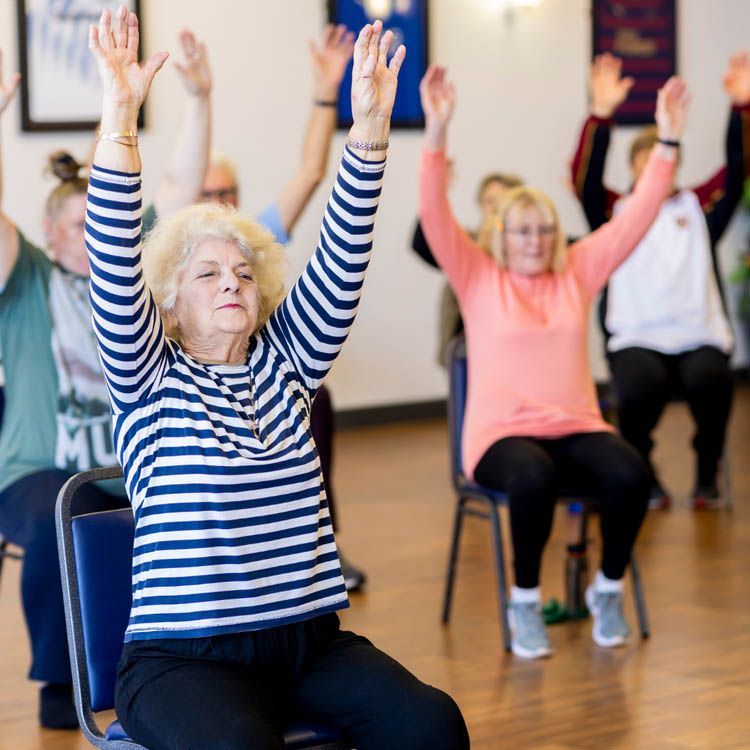 Seniorinnen und Senioren machen Gymnastik im Sitzen