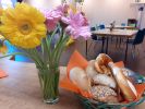 Frühstückstisch mit Brötchenkorb und Blumenstrauß im Vordergrund